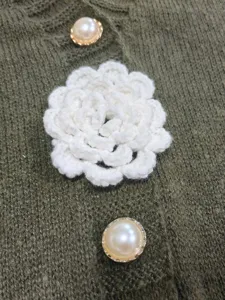 Exquisite detail of women knit cardigan vest with pearl buttons and white crochet flower style.