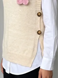 Primer plano de los botones laterales del chaleco de punto texturizado sobre camisa blanca.