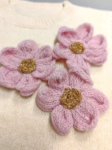 Vista detallada de flor tejida en rosa hecha a mano con centro dorado brillante para decoración.