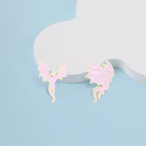 Dreamy pink and gold dragon enamel pins with star details on a light blue background