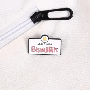 Detailansicht einer Bismillah-Emaille-Nadel mit Glockensymbol auf weißem Stoff