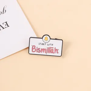 Nahaufnahme der Emaille-Brosche mit 'Bismillah'-Text und gelber Glocke auf beigem Grund