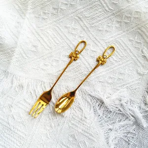 Detailansicht des eleganten goldenen Dessertlöffel- und Fruchtgabel-Sets mit Schleife
