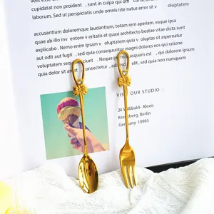 Nahaufnahme von goldenem Edelstahl Dessertlöffel und Gabel mit Schleife und Diamantgriff
