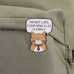 Primer plano detallado de un pin de esmalte de gato naranja con texto humorístico