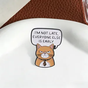 Primer plano detallado de un pin de esmalte de gato naranja con una frase humorística de oficina