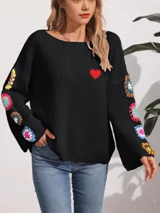Jersey negro de mujer con hombros descubiertos, mangas de ganchillo y parche de corazón.