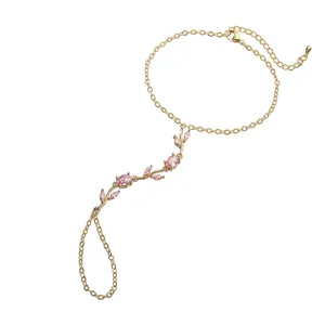 Détail élégant d'un bracelet-bague doré orné de cristaux de tulipes roses raffinés.
