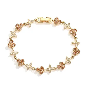 Macro detail of elegant gold-plated clover and butterfly bracelet with sparkling zircon stones