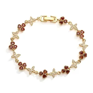 Detailed view of gold-plated clover and butterfly bracelet with red heart-shaped stones.