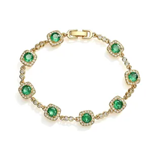 Close-up of gold-plated bracelet featuring green square halo cubic zirconia stones.