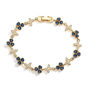 Close-up of golden bracelet with blue clover and crystal butterfly charms