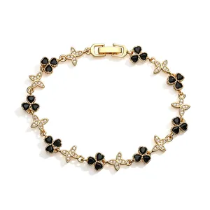 Detail view of gold-tone bracelet with black clover and butterfly cubic zirconia charms