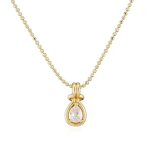 Close-up detail of a teardrop zircon pendant on a dainty gold bead chain necklace