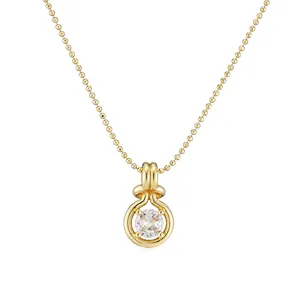 Detailed close-up of a gold-plated round knot pendant necklace with a clear zircon stone
