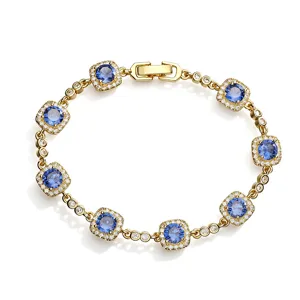 Detailed macro shot of gold bracelet with sparkling blue stones in halo setting.