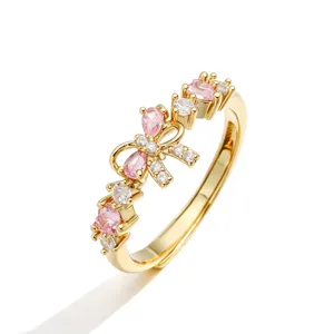 Dettaglio ravvicinato di un anello dorato regolabile con fiocco e pietre rosa.