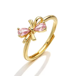 Dettaglio di un anello regolabile dorato con un design a fiocco in pietre rosa chiaro