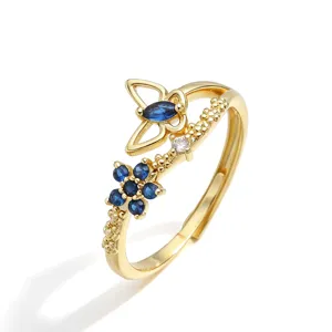 Dettaglio ravvicinato di un anello dorato regolabile con farfalla e pietre blu