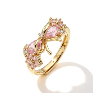 Dettaglio di un elegante anello a fiocco dorato con cristalli rosa e fascia regolabile