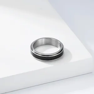 Détail d'une bague rotative minimaliste en acier titane avec incrustation de fibre de carbone