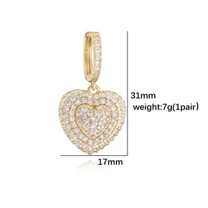 Detail view of heart-shaped drop earrings with clear stones and gold plating
