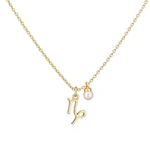 Close-up of gold Capricorn zodiac necklace with small pearl charm on white background