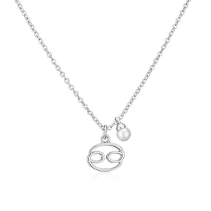 Macro detail of Cancer zodiac symbol pendant with a white pearl on a silver necklace.