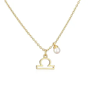 Macro view of a gold Libra zodiac symbol pendant necklace accented with a round white pearl