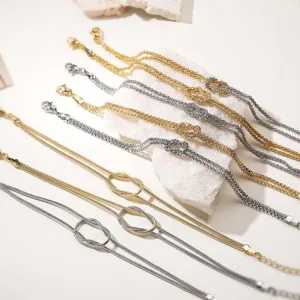 Vista dettagliata dei braccialetti con nodo dell'infinito in oro e argento su pietra bianca.
