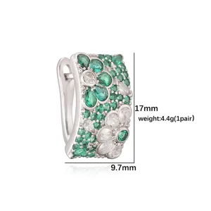 Detailweergave van elegante bloemen oorring met groene en witte kristallen