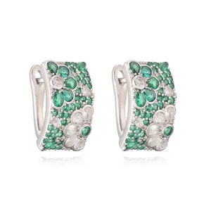 Detailopname van elegante oorringen met groene en witte madeliefjespatronen.