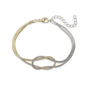 Dettaglio del nodo dell'infinito bicolore su un bracciale a doppia catena a serpente.