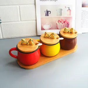 Close-up detail of ceramic seasoning jars with wooden lids and gold bow handles on a tray.