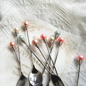 Detailaufnahme niedlicher Edelstahllöffel und Gabeln mit bunten Perlengriffen für Desserts