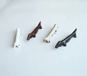Quatre repose-baguettes en céramique en forme de teckel coloré sur un fond clair uni