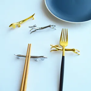 Detail shot of creative gold and silver animal-shaped metal chopstick rests on a table