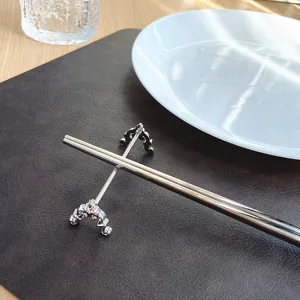 Close-up of luxury carved stainless steel chopstick rest on a dark mat