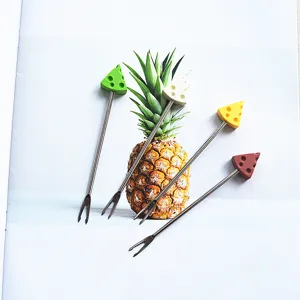 Detailed shot of cute cheese shaped stainless steel fruit forks arranged with fresh pineapple prop.
