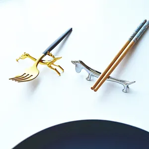 Detail view of golden deer and silver dachshund metal chopstick rests with cutlery