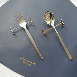 Détail de repose-couverts en acier inoxydable argent et or tenant une fourchette et cuillère