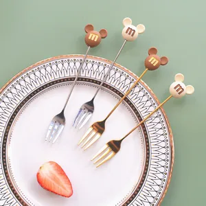 Detail shot of cute stainless steel fruit forks with cartoon ear designs, ideal for cakes and desserts.