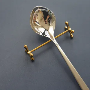 Détail d'un repose-couverts en acier inoxydable doré avec une cuillère brillante