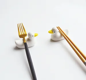 Gros plan de repose-baguettes en céramique canard blanc avec fourchette et baguettes