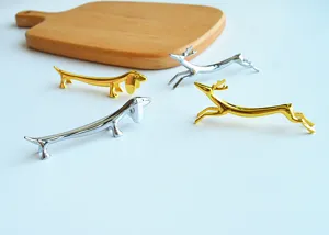 Detail view of golden and silver metal chopstick rests in dachshund and deer shapes