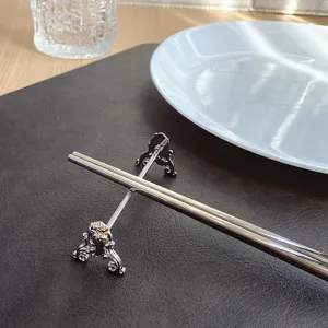 Close-up of a silver stainless steel carved chopstick rest on a dark leather mat