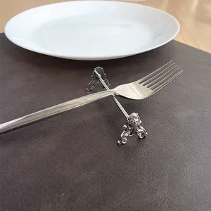 Close-up of ornate silver stainless steel cutlery rest holding a fork on leather mat