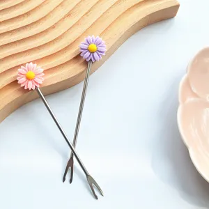 Nahaufnahme Detail von Edelstahlobstgabel mit süßem rosa und lila Gänseblümchen Blumendekor.