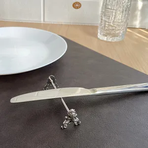 Elegant ornate silver cutlery rest supporting a stainless steel knife on a placemat.