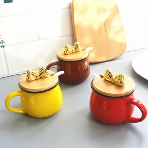 Close-up of cute ceramic seasoning jars featuring wooden lids and shiny gold bow handles for kitchen.
